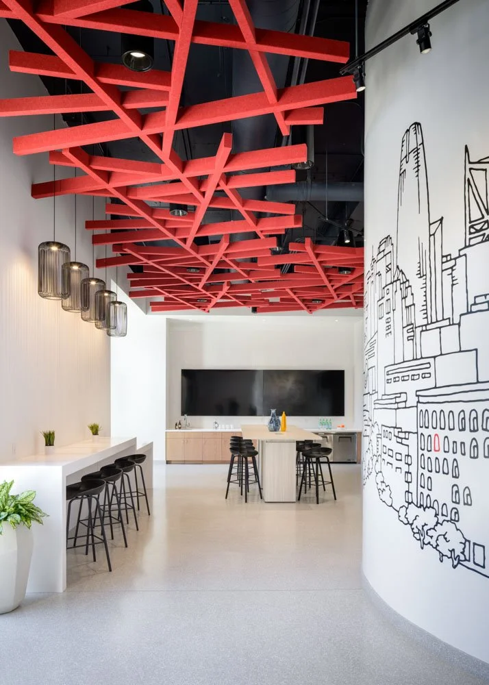 modern office break area with mural, red acoustical ceiling baffles, bar, island, and tv monitors