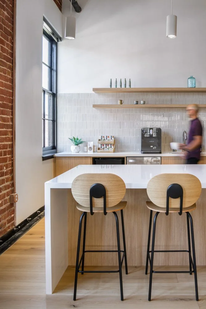 detail of a modern white kitchen island with bar stools and beige tiles, man walking