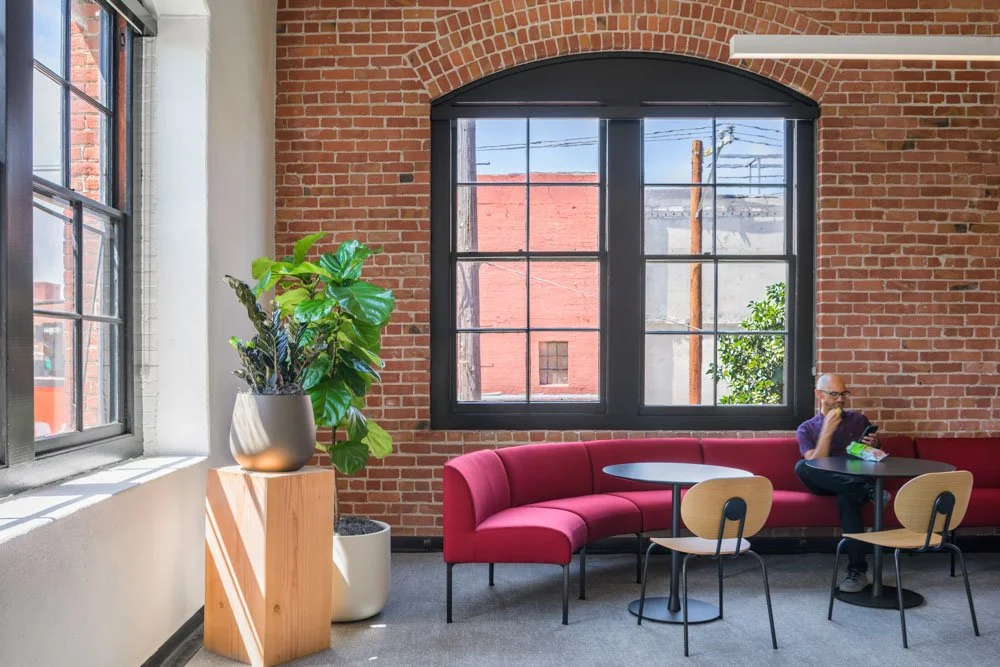 red banquet seating with man at table, brick wall, large windows