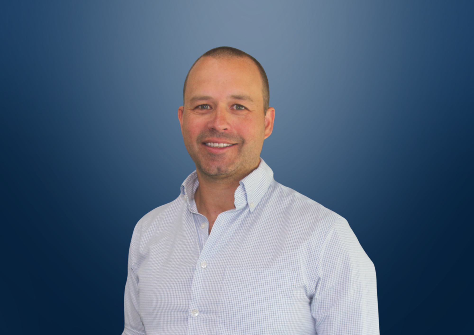 Headshot of a man, David Blamey, in a dark suit and white shirt smiling against a blue background.