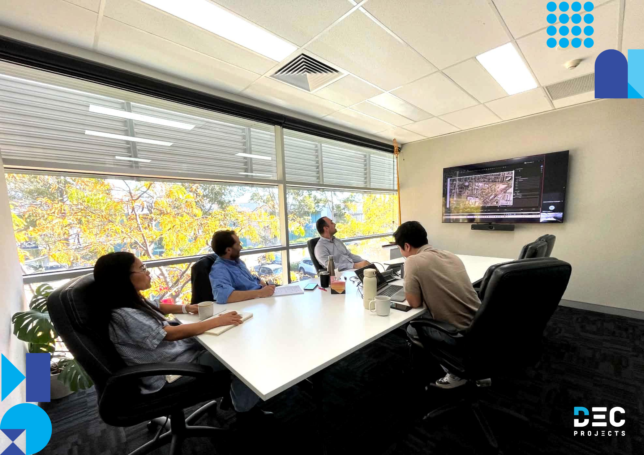 DEC Projects estimators in a training session reviewing construction plans on screen, focusing on Bluebeam quantity take-offs and estimating workflows in a modern office meeting room.