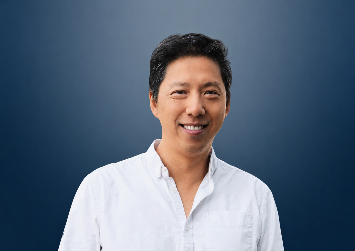 Professional man, Eric Lai, in a white shirt and black blazer posing against a blue gradient background.