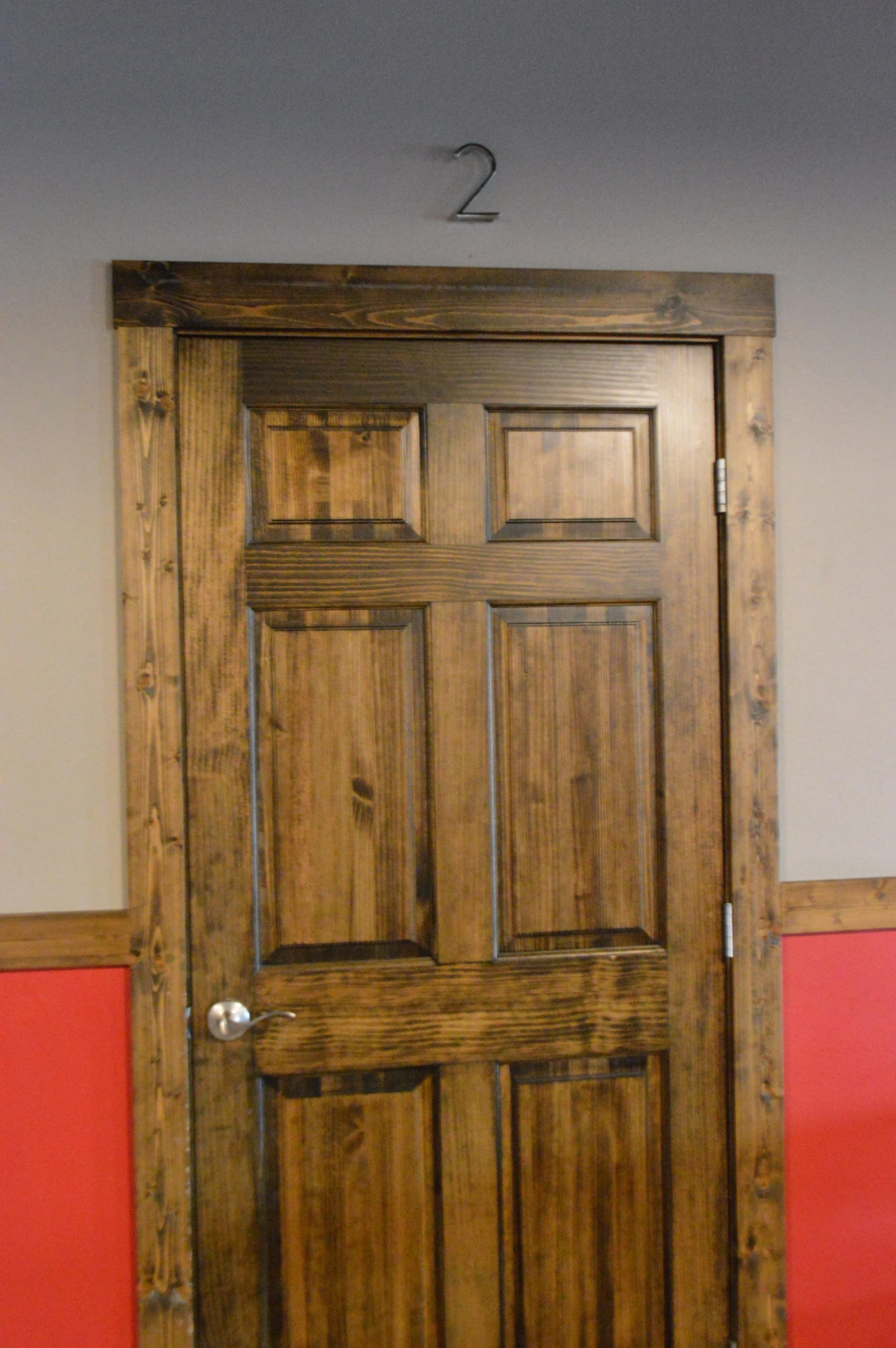 Wooden door with numbered sign '2' above it in a hallway.