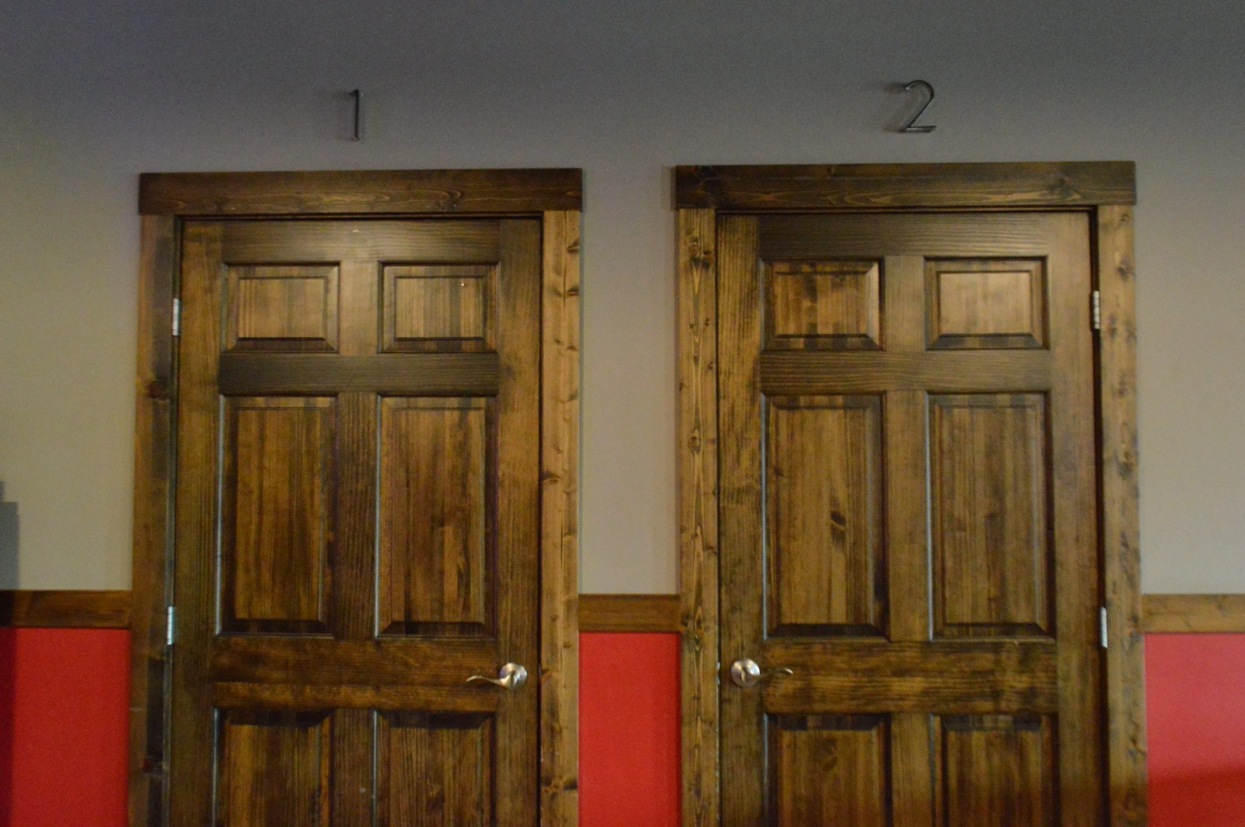 Two wooden doors labeled 1 and 2, set in a wall with beige and red sections.