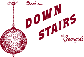 A promotional sign with a red disco ball and text reading 'Check out Down Stairs at Georgie's' in red and dark purple.