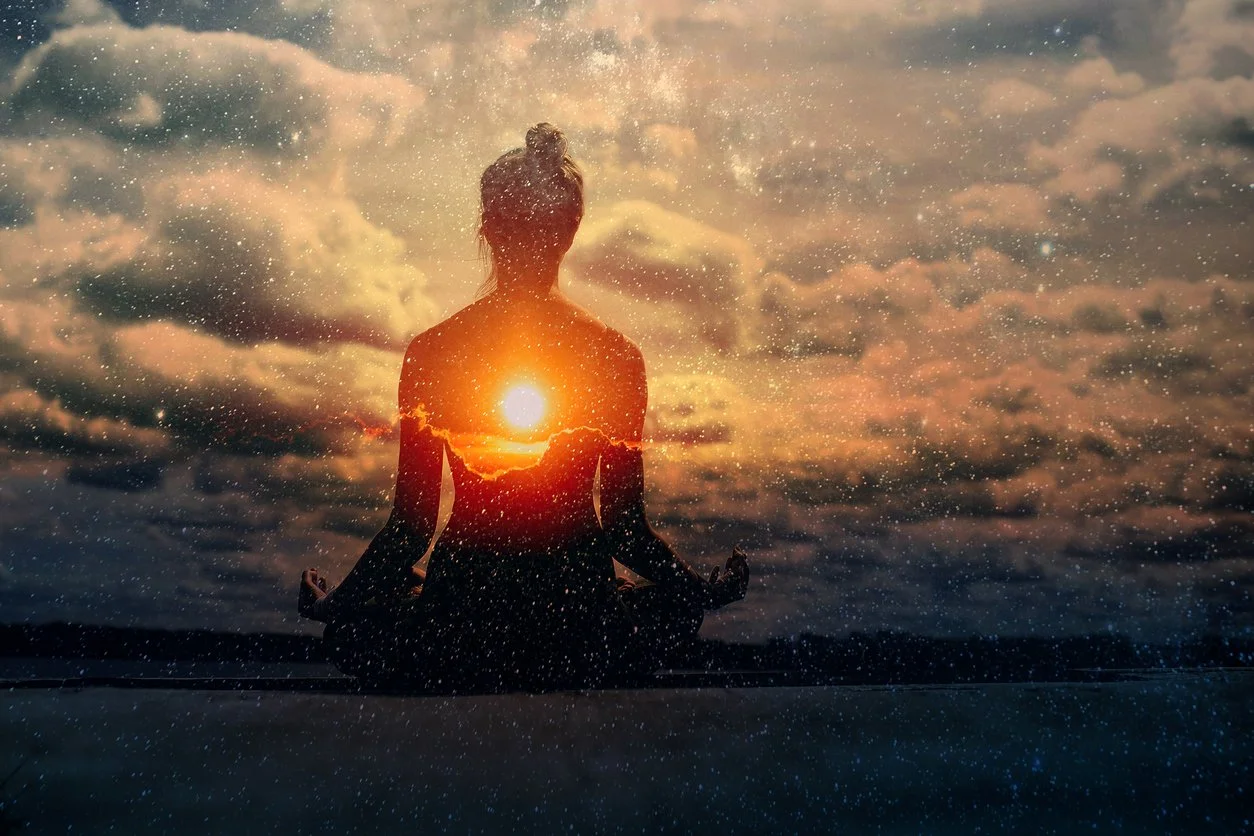 A woman practicing yoga outdoors at sunset, with the sun positioned behind her, creating a glow around her silhouette. The sky is filled with clouds, and the image has a dreamy, mystical atmosphere with sparkling effects.