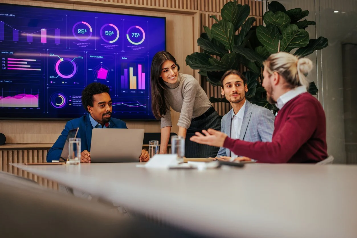 A woman with short hair standing on a rocky beach during sunset with her arms outstretched and her face turned upwards toward the sky.