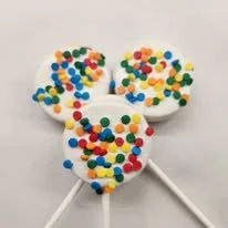 Three white lollipops decorated like Mickey Mouse heads with colorful sprinkles on top.
