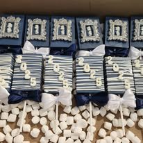 Display of blue gift boxes with white ribbons, stack of white chocolate bars, and heart-shaped white candies.