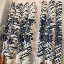 Close-up of five cream-filled pastries topped with white and dark chocolate drizzle.