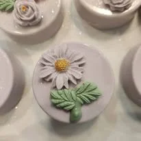 Frosted sugar cookie decorated with a daisy and leaves made from icing.