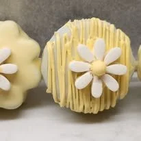 Close-up of decorated cupcakes with yellow and white icing, featuring white daisy-like flowers.