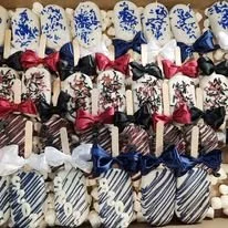 Row of wrapped gift boxes with striped and patterned wrapping paper in blue, black, pink, and white, adorned with matching ribbons and bows.