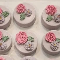 Six decorative cookies with pink roses and green leaves on a white background.