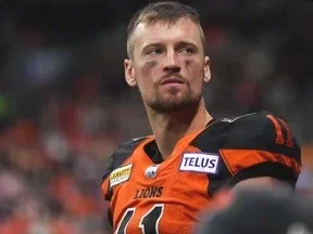A man in an orange and black sports jersey looking off into the distance with a serious expression.