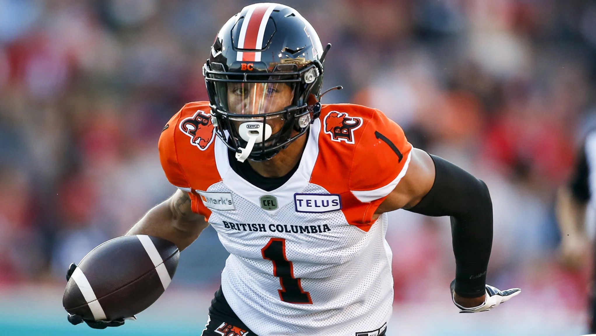 A football player wearing an orange and white jersey with the number 1 on it, a helmet, and black arm sleeves, running with the football in his right hand during a game.