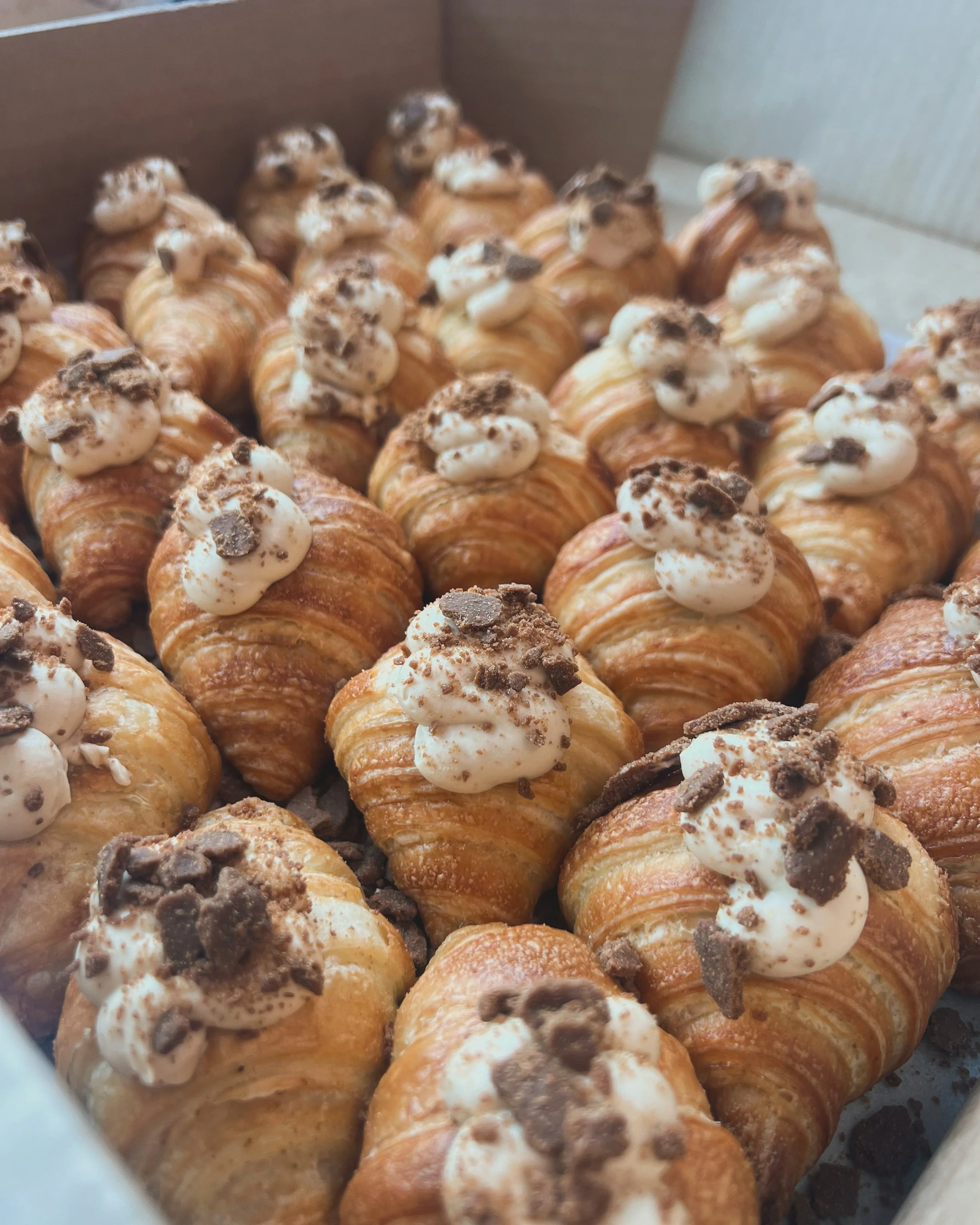 Tray of chocolate cream-filled croissants topped with bits of chocolate.