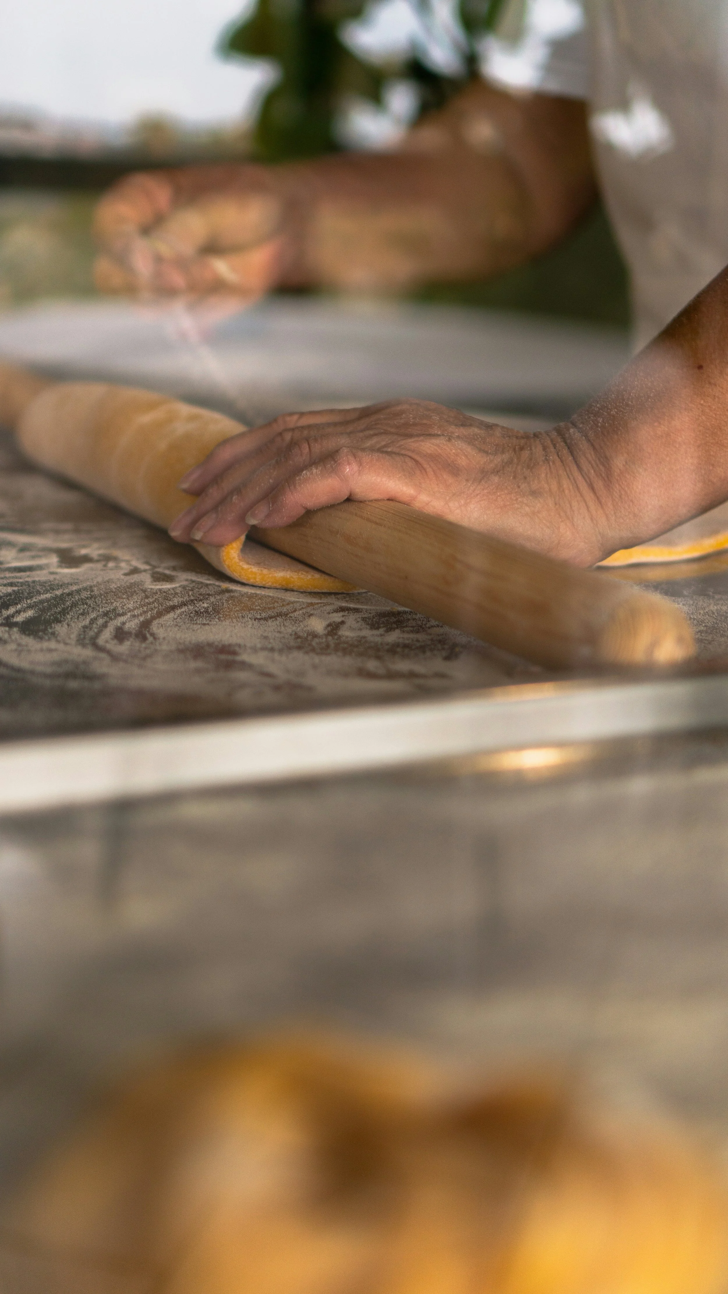 Hands rolling out dough with a rolling pin on a floured surface.