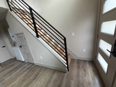 View of a home's interior entryway with a staircase leading upwards, a white door with frosted glass panels, and light-colored walls and flooring.