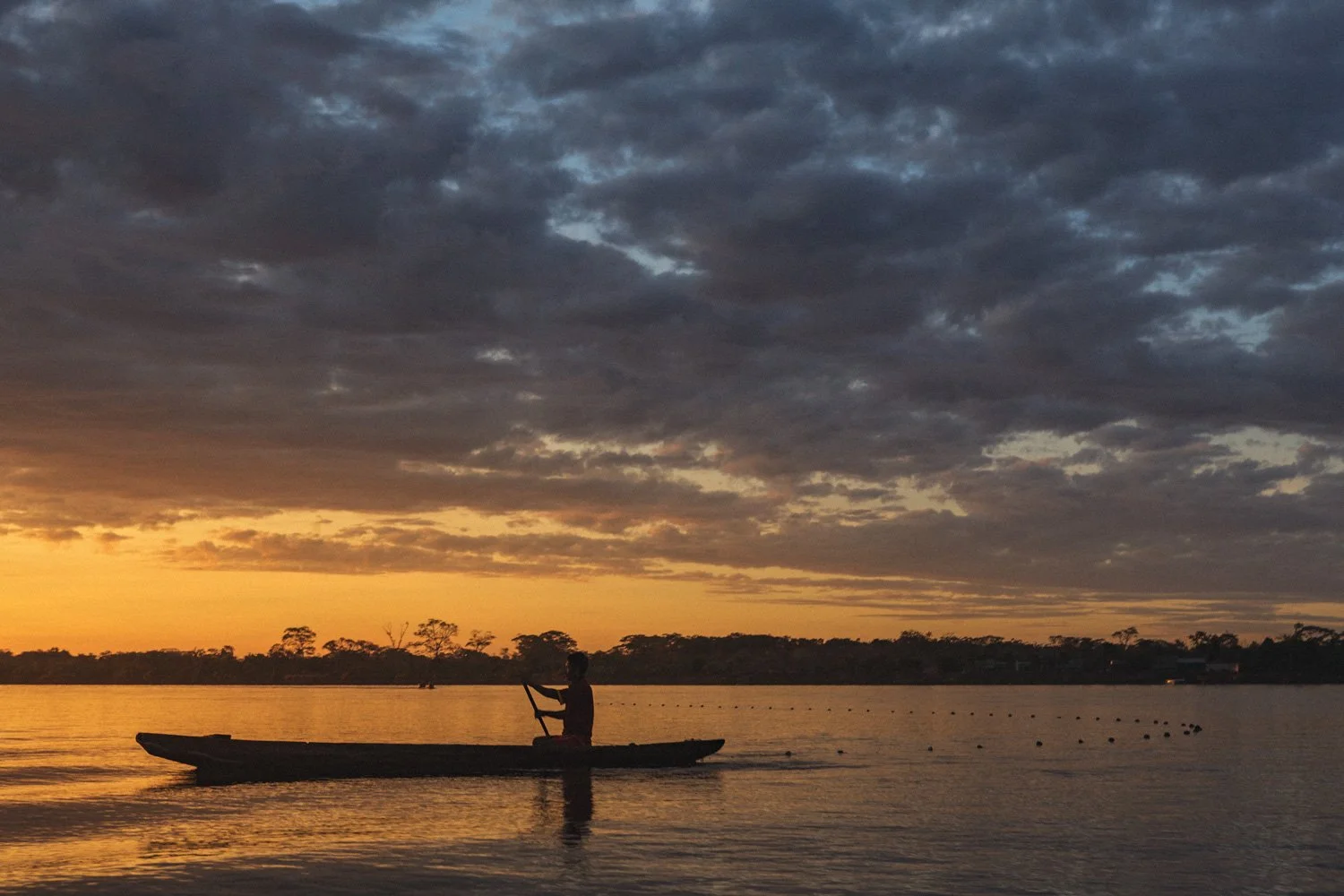 A fisherman casts his net in hopes of catching fish at sunrise.