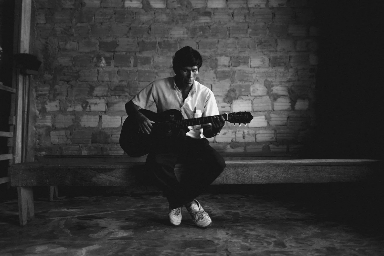 Older man practices his guitar after class in the Amazon.