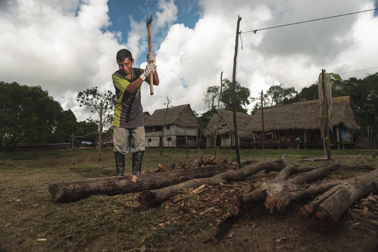 A villager chops wood in preparation for building a canoe used to transport preserved fish to market along the Amazon River.