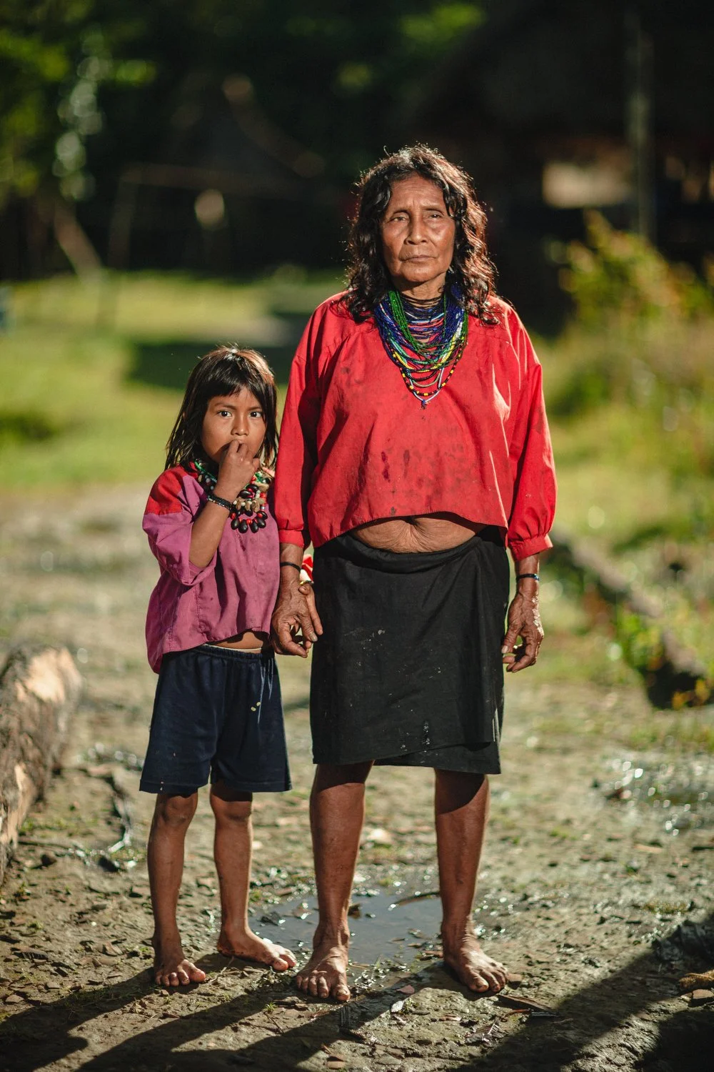A grandmother and child stand together in their village, representing the passing of traditions and resilience of faith along the Amazon River.