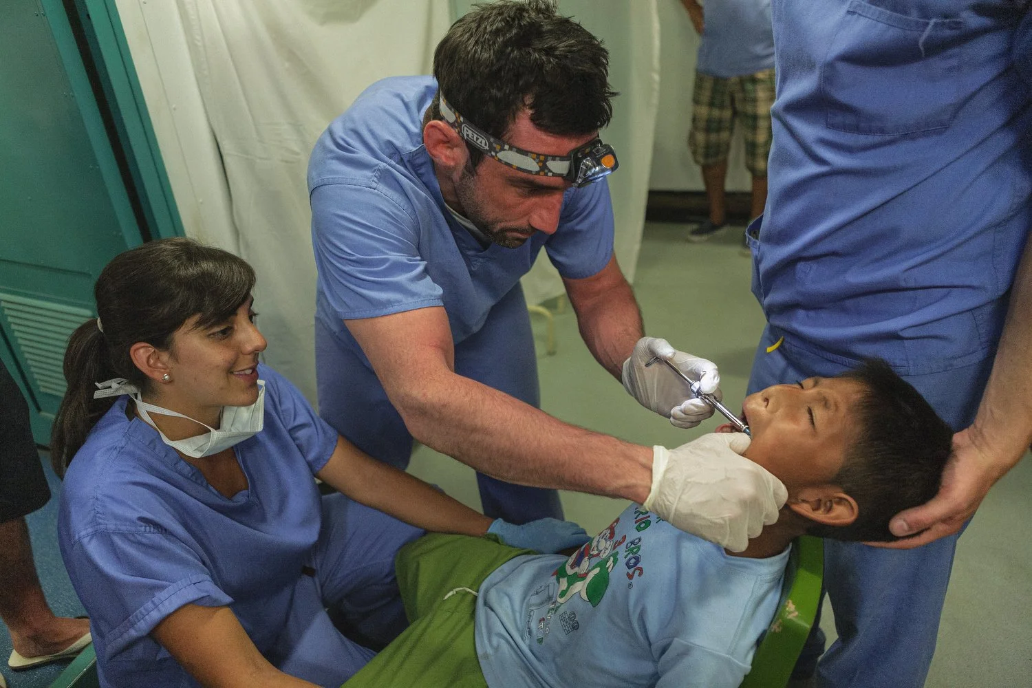 Dentists work together to perform a procedure for a young boy aboard the Amazon Hope.