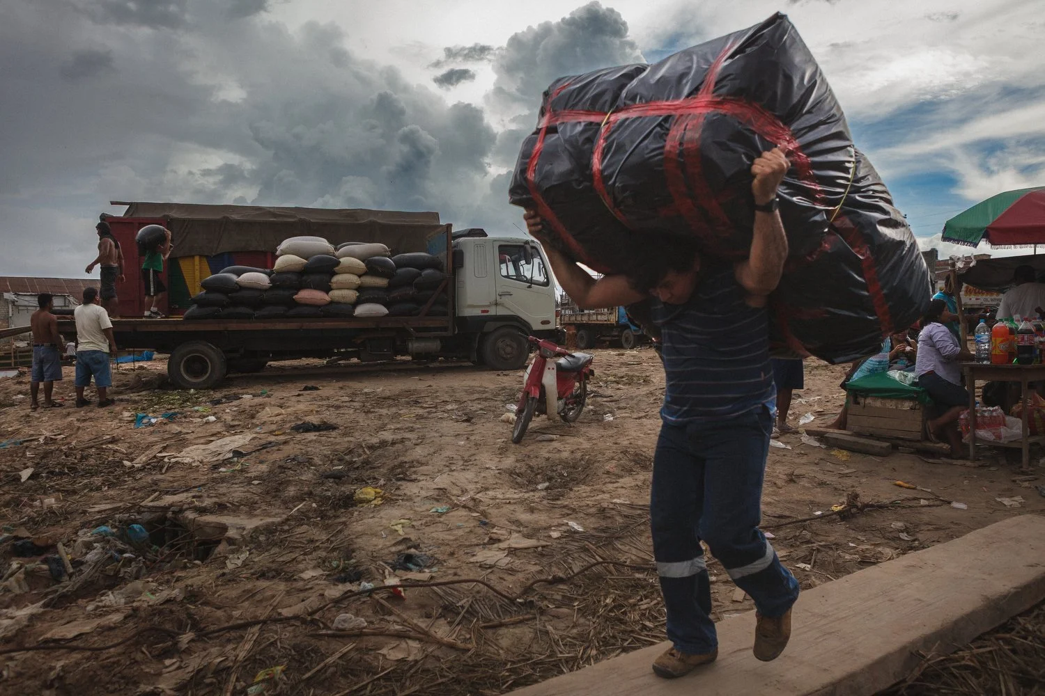 A worker in Iquitos carries a heavy bundle from the docks, showcasing the physical demands of daily labor in the Peruvian Amazon.