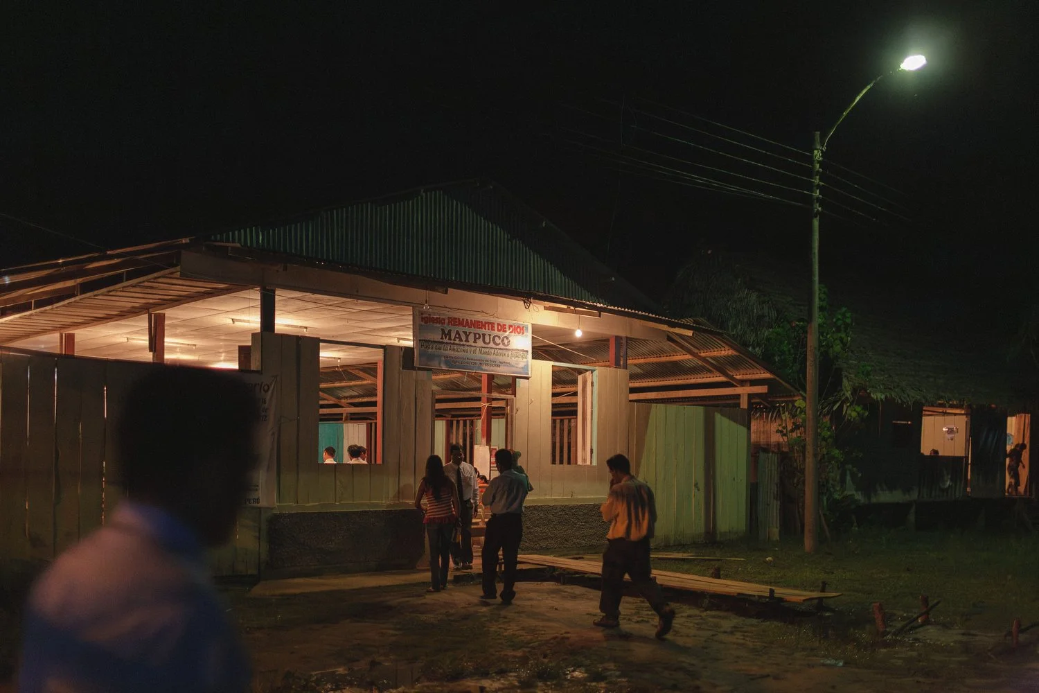 People entering church building at night in Maypuco, Amazon, Peru.