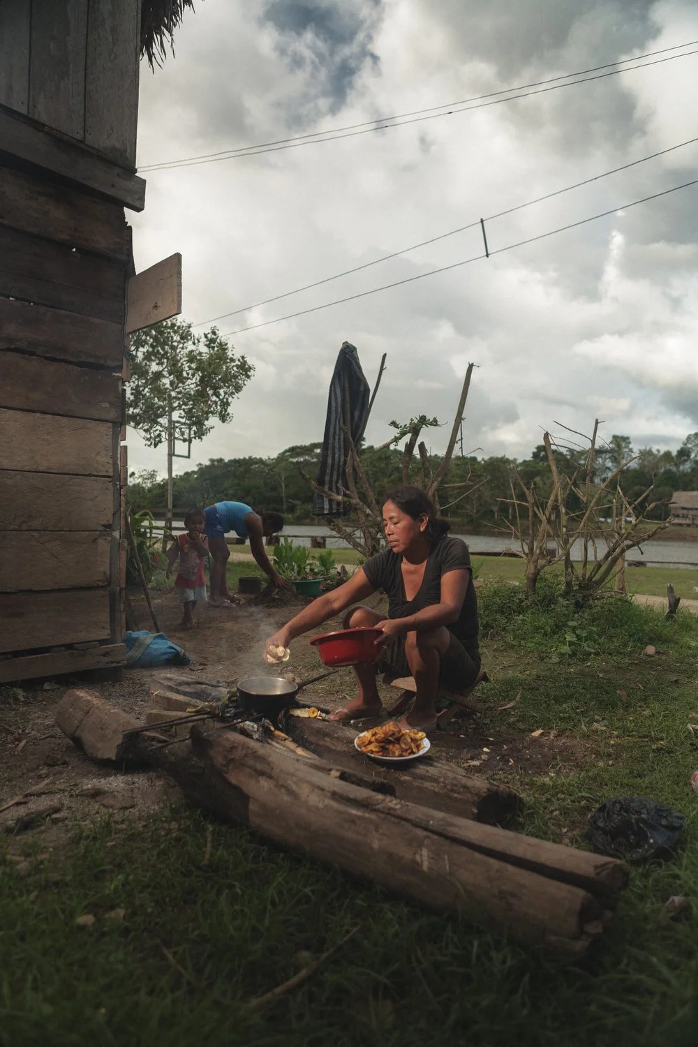 A woman cooks plantains and local food over an open fire outside her home in a riverside Amazon village.