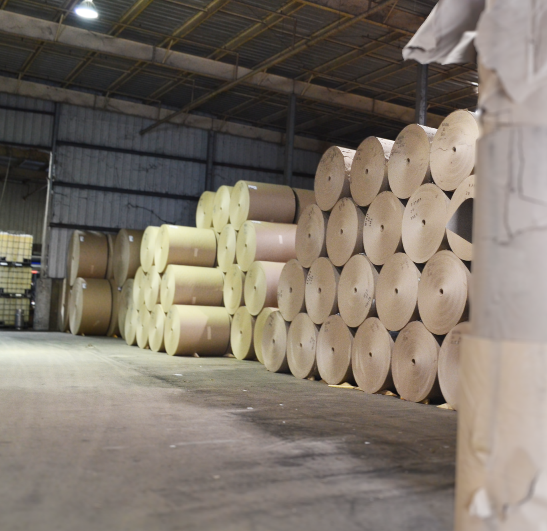 Stacked large rolls of paper in a warehouse.