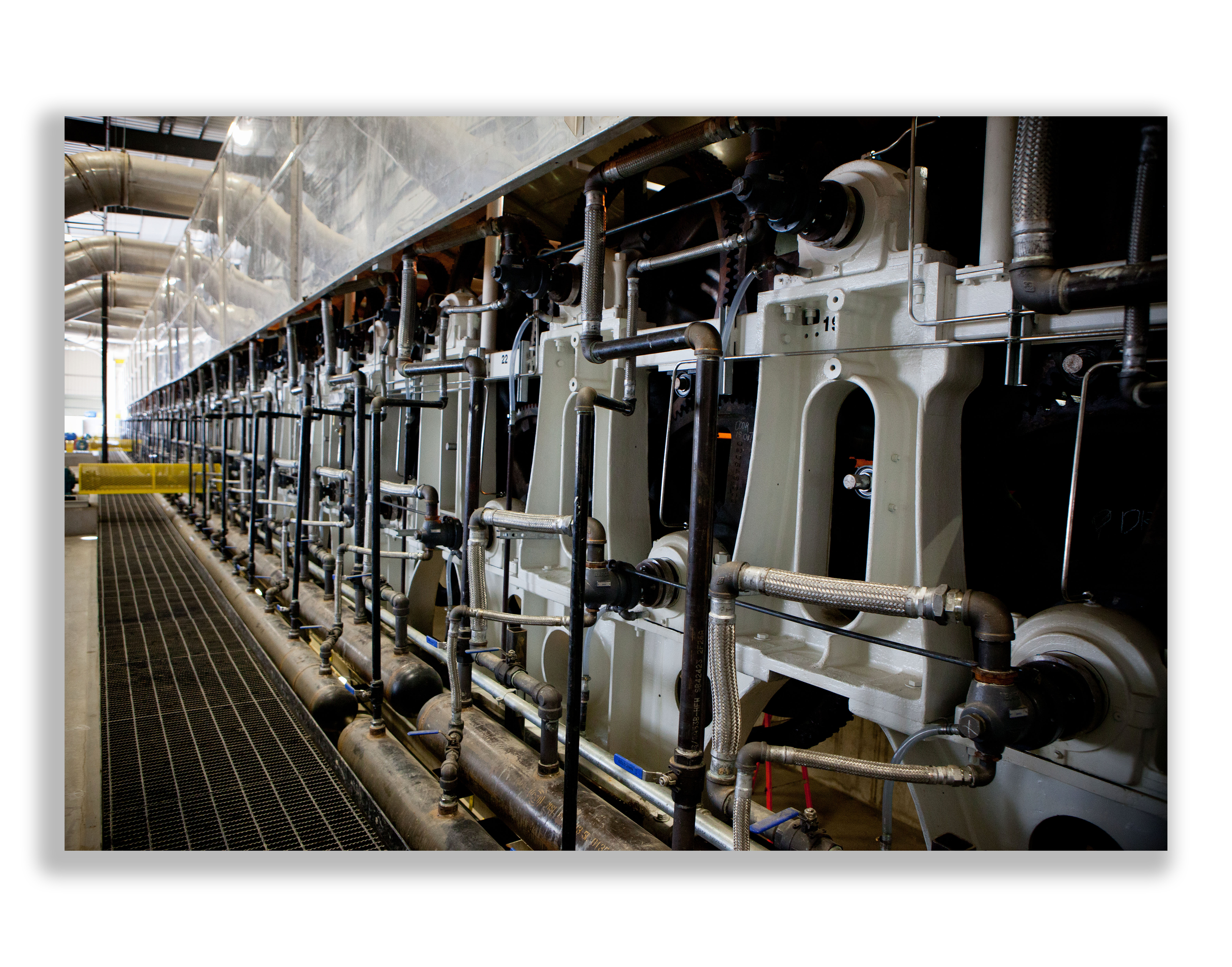 Industrial machinery with numerous pipes, valves, and fittings stored on a factory or plant floor.