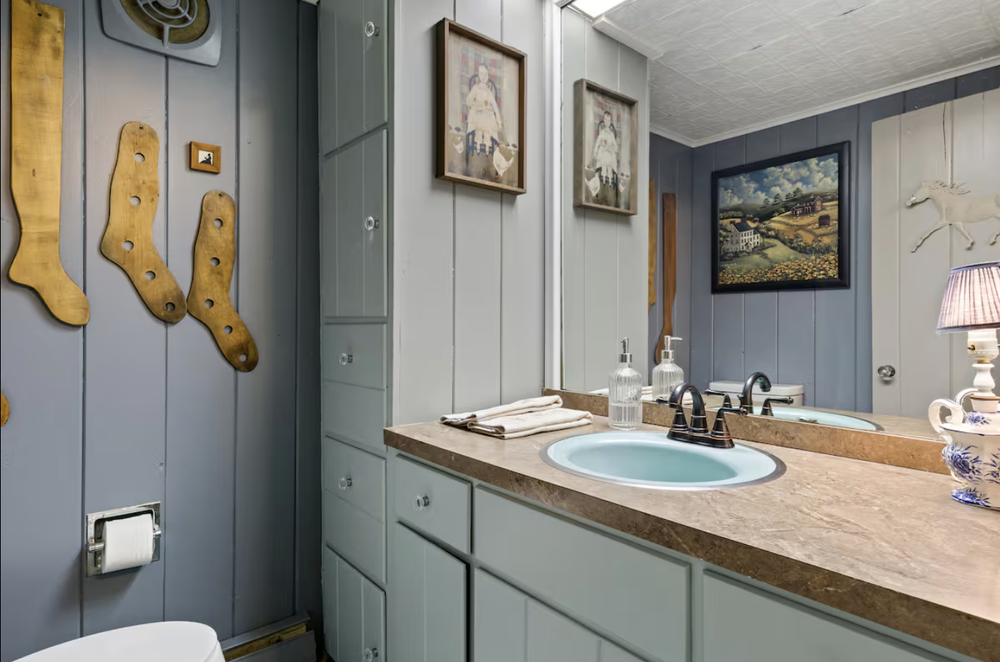 Unit 1 half bath with vanity, mirror, and classic main house details