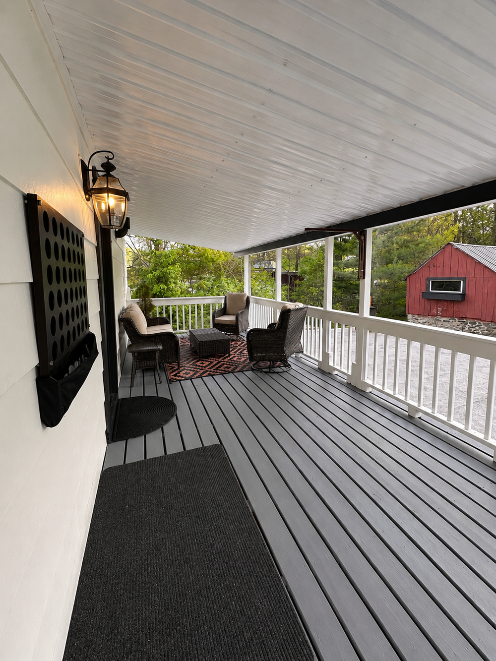 Back deck view near the entrance wall with outdoor furniture and covered seating