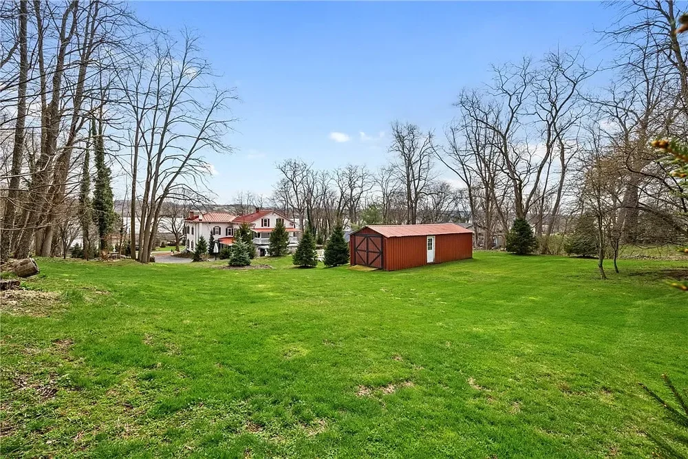 Wide backyard lawn view with shed and mature trees