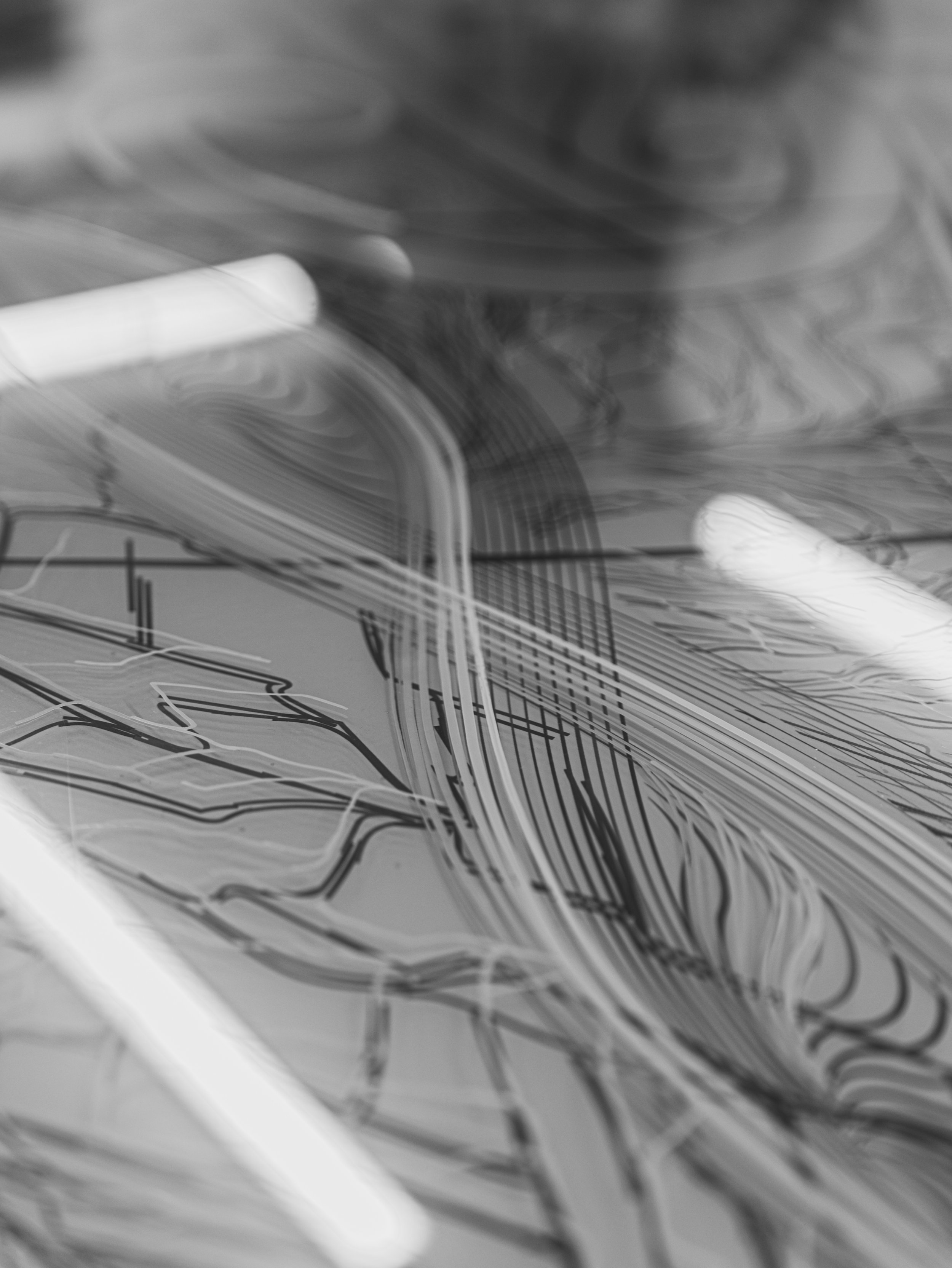Abstract black-and-white close-up of a shiny surface with swirling and intersecting lines, possibly a drawing or digital art.