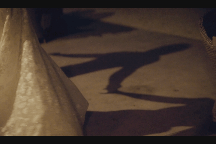 Close-up of a beige fabric covering a small area on a surface, with shadows cast on the ground in low light.
