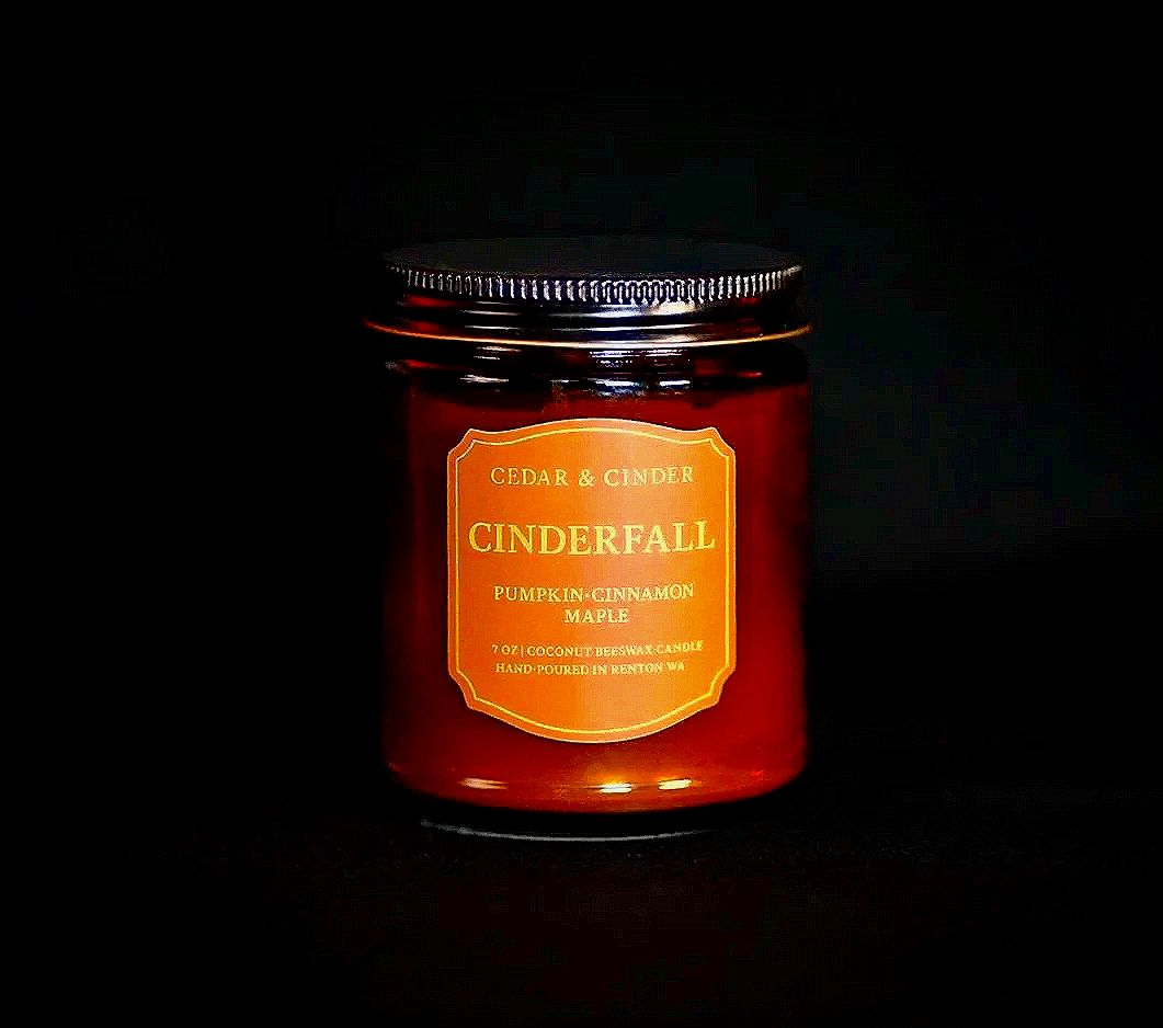 Candle jar labeled 'Cinderfall' with scent notes of pumpkin, cinnamon, and maple.