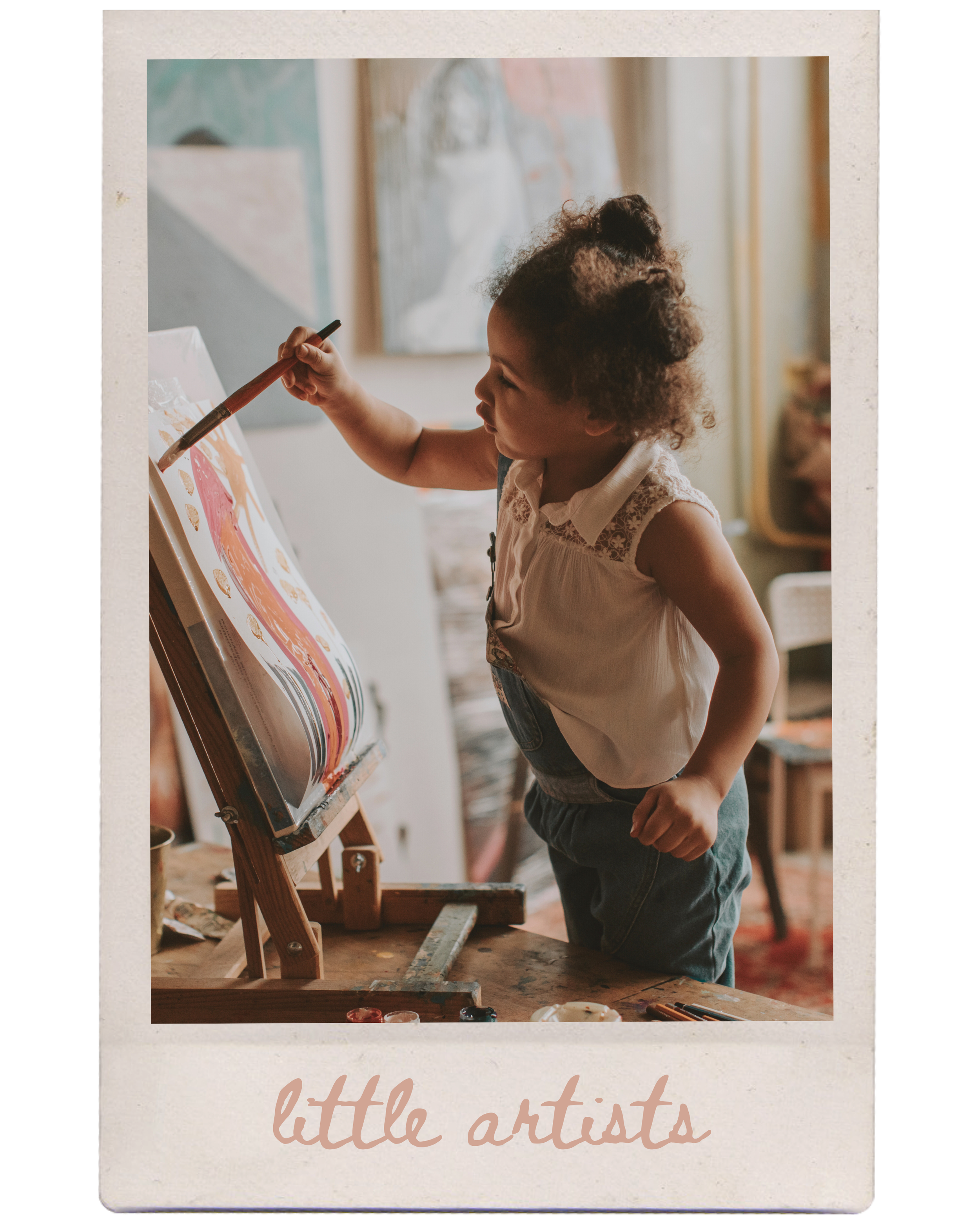 A young girl with curly hair painting on an easel in a cozy art studio.