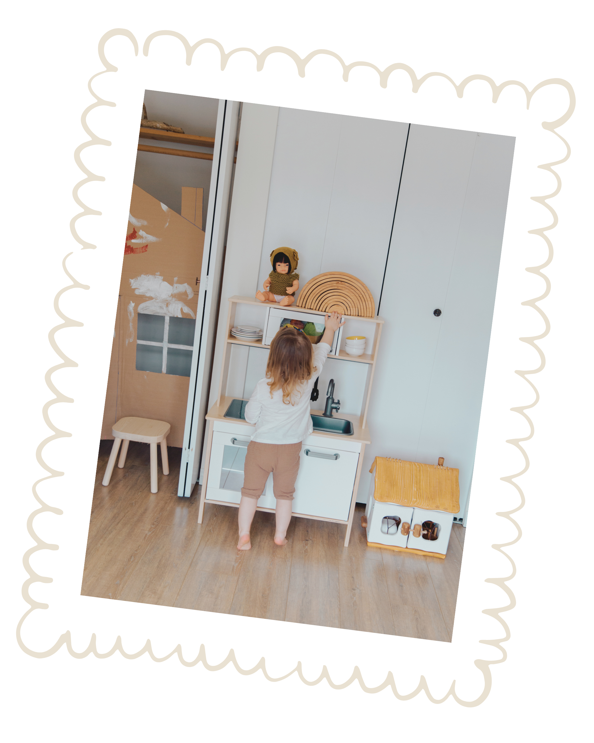 Child playing with a doll on a small play kitchen.