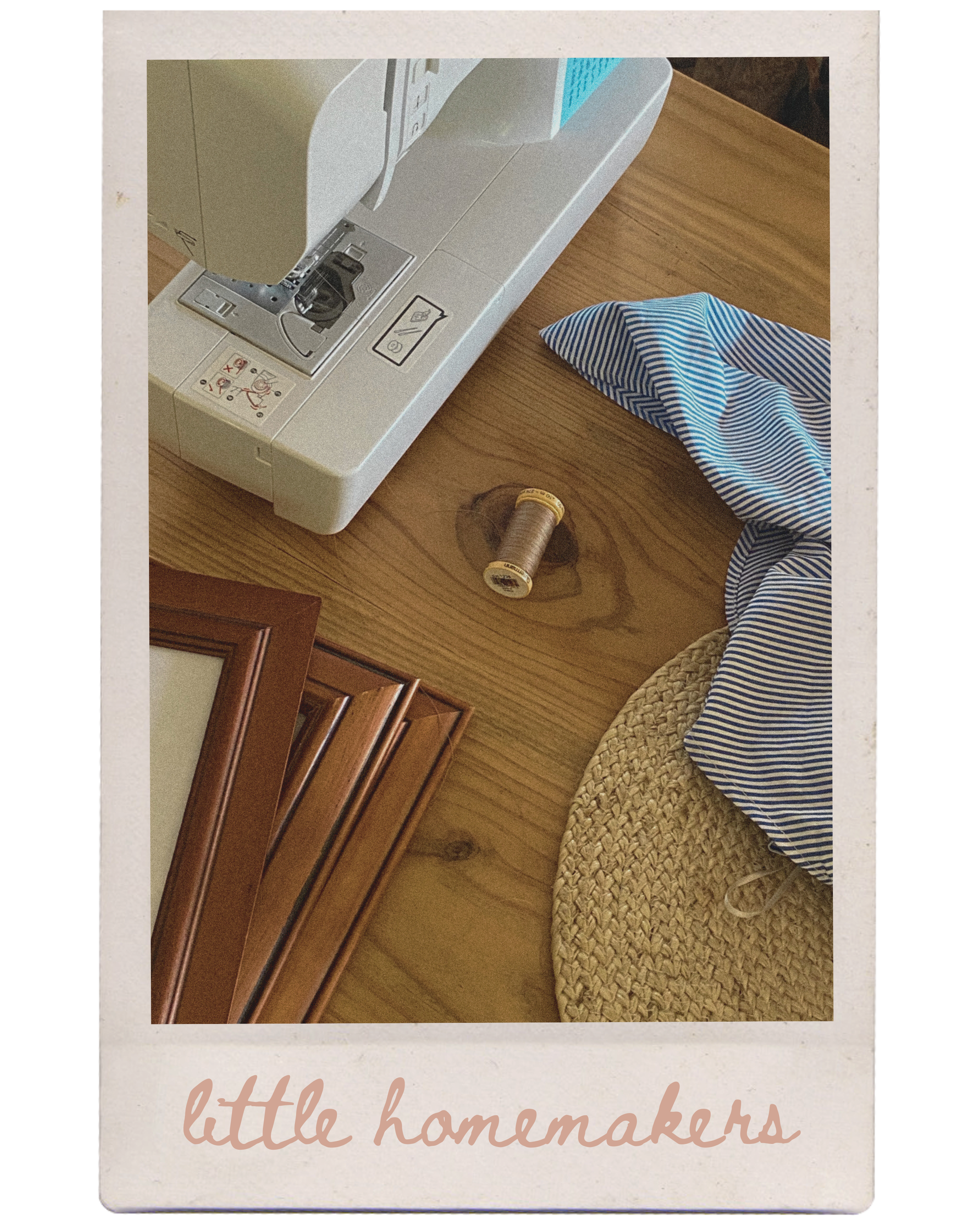 A sewing machine on a wooden table with a spool of thread and a blue striped piece of fabric nearby, and the words "little homemakers" written at the bottom of the image.