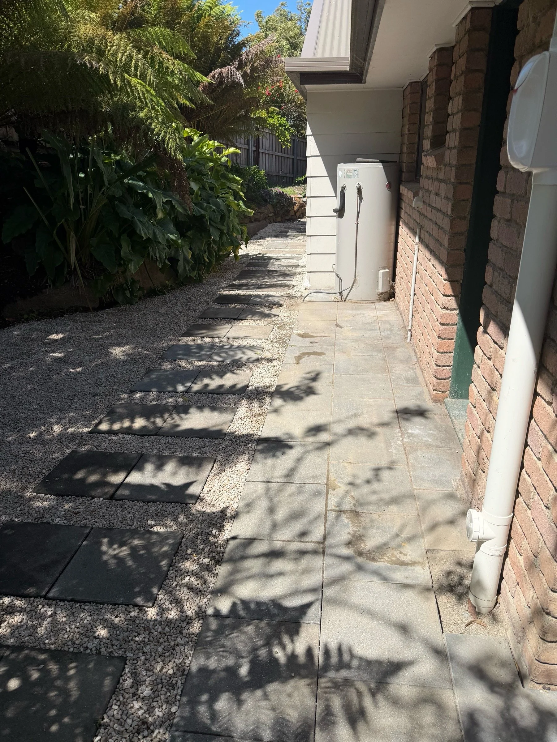 Freshly installed gravel and paving amongst a ferny backyard