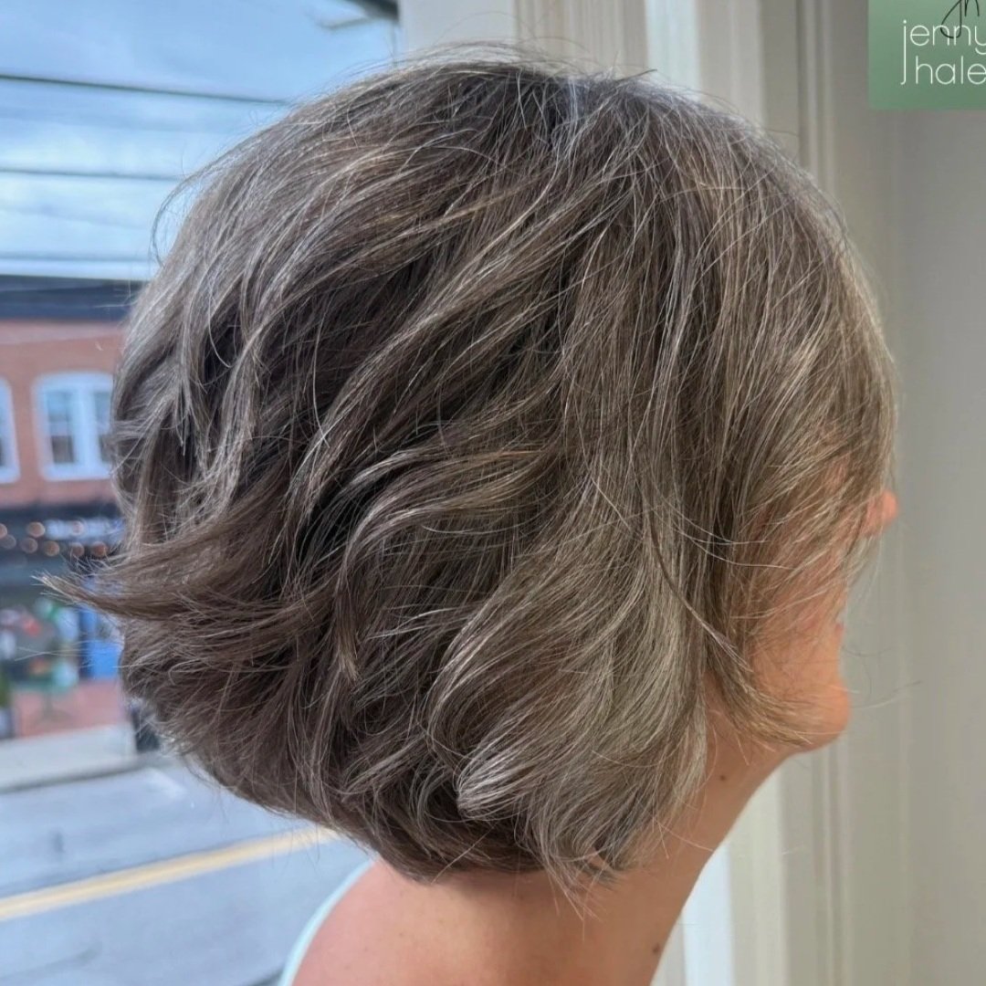 Side view of a woman with short, wavy gray hair.