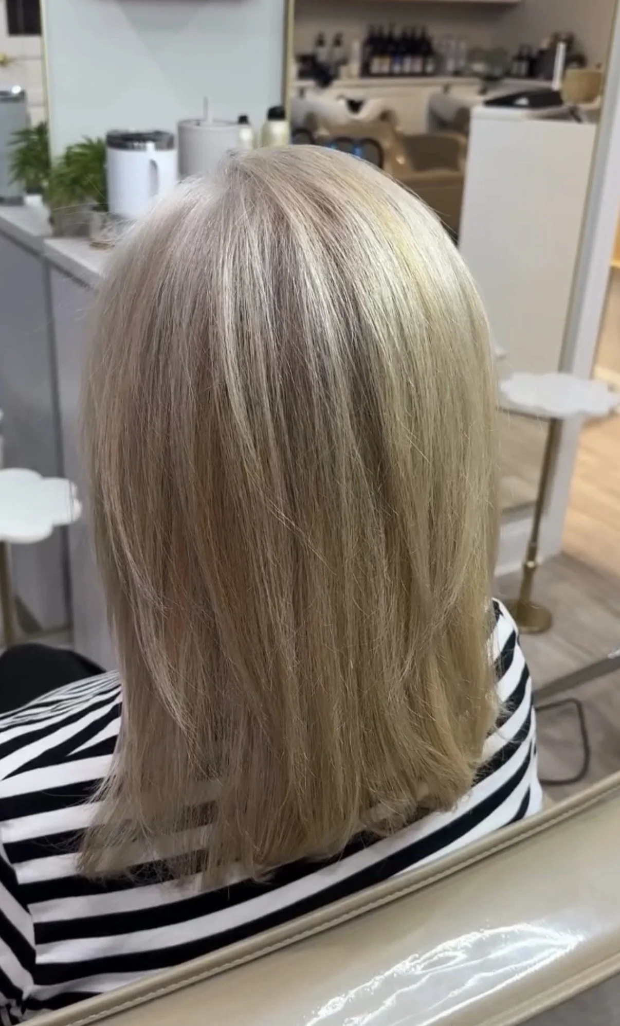 A person's head with blonde hair viewed in a salon mirror.