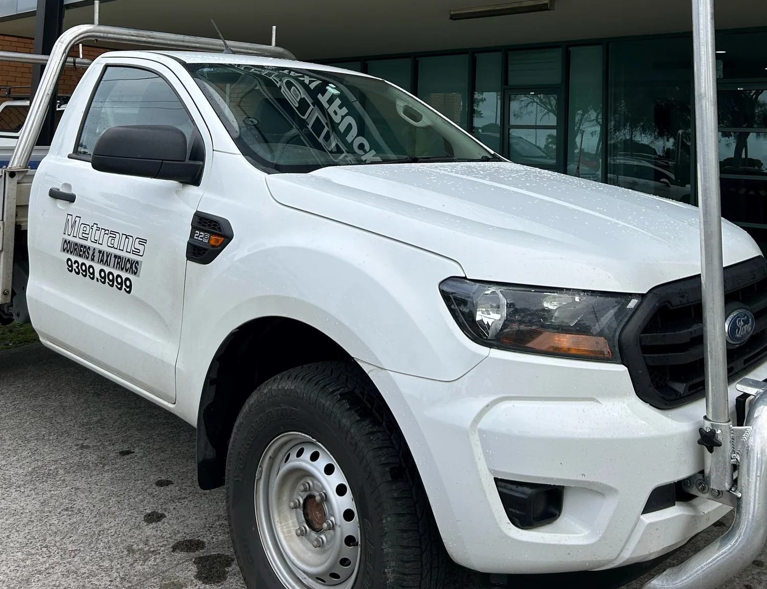 A Metrans white courier and taxi truck parked outside a building