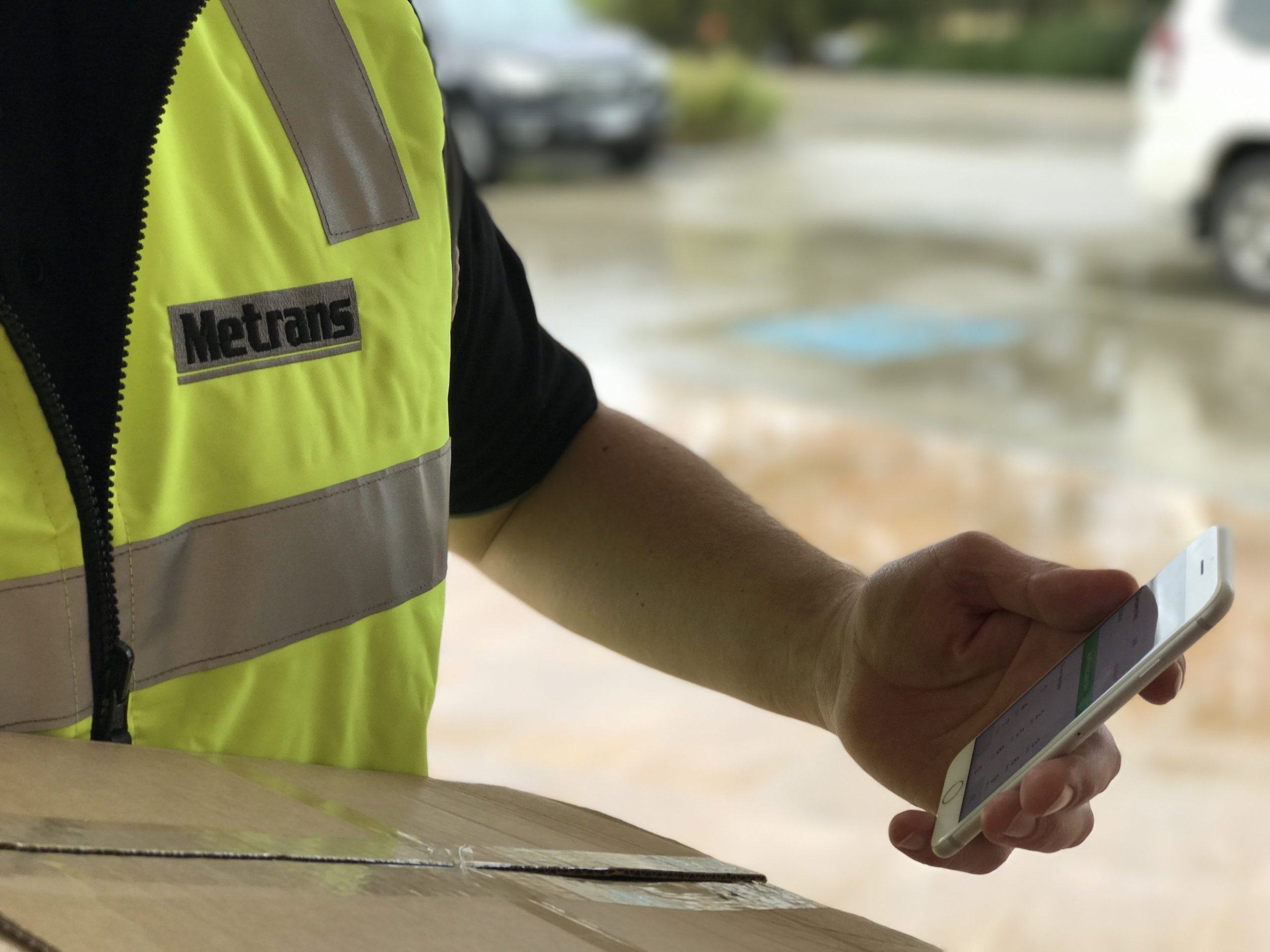 Metrans driver in high-visibility workwear using a phone beside a transport vehicle