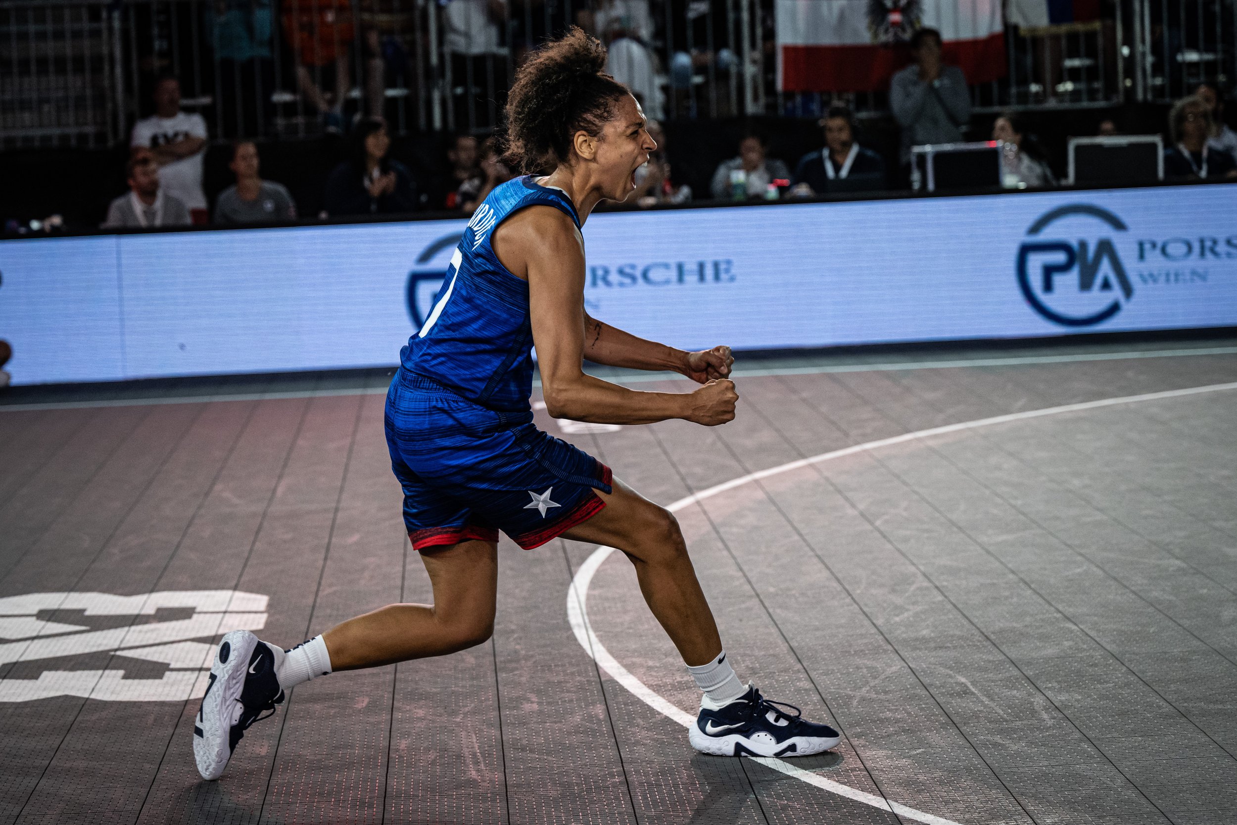 Cierra Burdick playing basketball, celebrating on the court during a game, with spectators watching in the background at the Paris Summer Olympics.