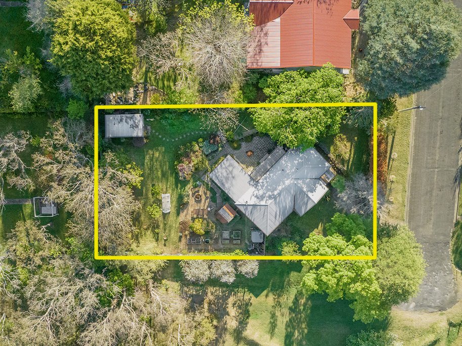Aerial view of a backyard with a house, trees, and garden area, outlined in yellow.