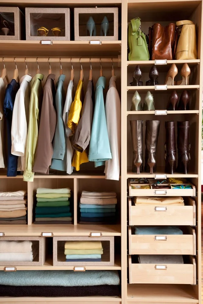 Closet with folded clothing, hanging shirts, and shelves with shoes, handbags, and storage boxes.